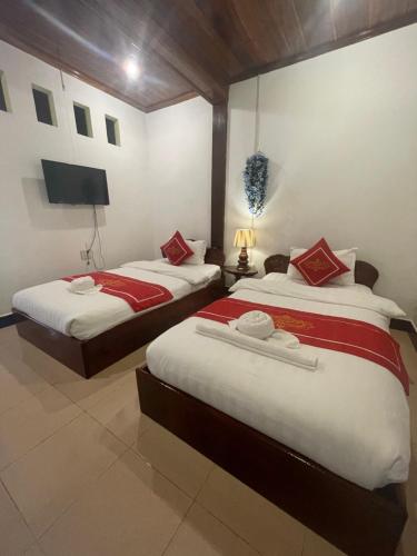 a bedroom with two beds and a flat screen tv at Ouis NamKhan Place House in Luang Prabang