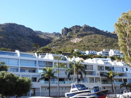 un hotel con palmeras y una montaña en el fondo en 24 Gordonia, Sleeps 7, Beach Front condo - Load-shedding friendly with Solar Power and battery backup, en Gordonʼs Bay