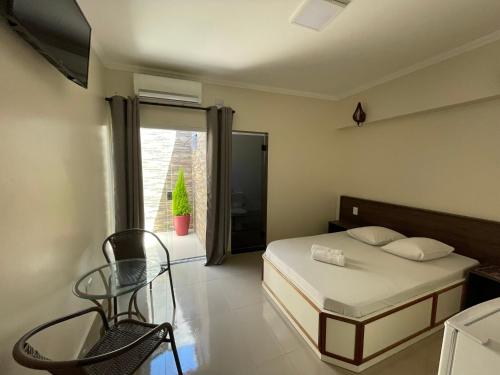 a bedroom with a bed and a chair and a window at Hotel Novo Apúlia in Sao Paulo