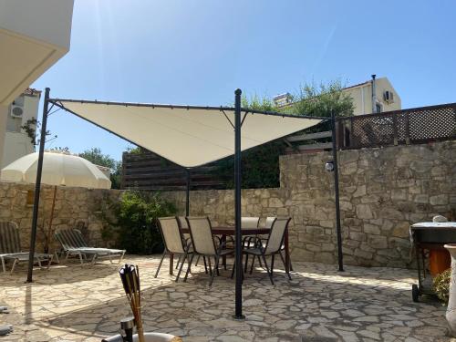 a table and chairs under a white umbrella on a patio at Maison à côté lac proche mer FANOU HOUSE in Georgioupoli