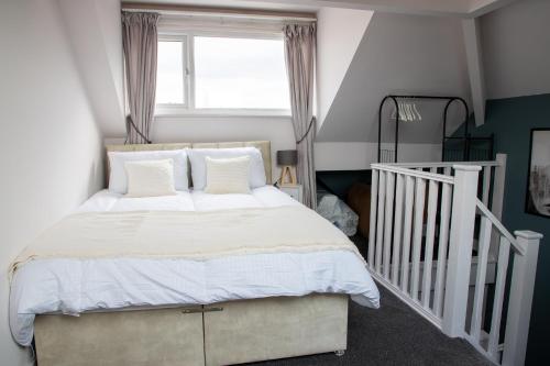 a bedroom with a bed with white sheets and a window at Beach Apartments - 1st Floor Cleveleys in Cleveleys