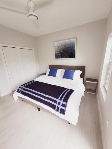 a white bedroom with a large bed with blue pillows at Modern 2 bedroom walking distance to the beach! in West Bay