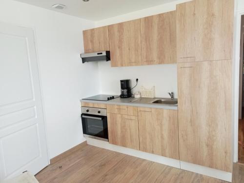 uma cozinha com armários de madeira e um lavatório em Gite de la margeride em Thoras
