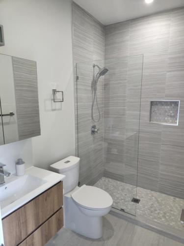 a bathroom with a toilet and a glass shower at Modern 2 bedroom walking distance to the beach! in West Bay