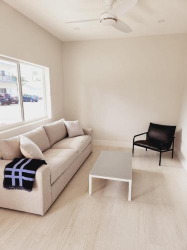 a white living room with a couch and a chair at Modern 2 bedroom walking distance to the beach! in West Bay