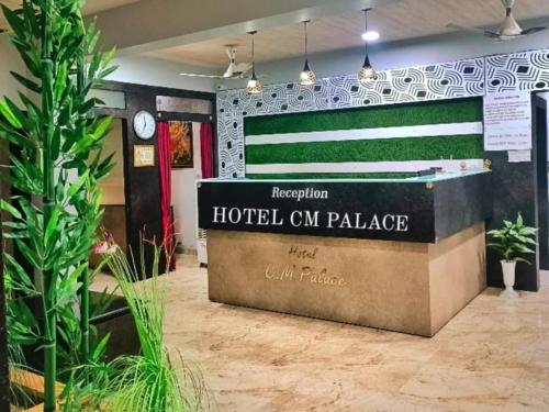 un cartel del palacio de un hotel en un cuarto con plantas en HOTEL CM PALACE & GUEST HOUSE & P.G ROOMS, en Kalol