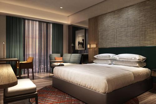 クチンにあるSheraton Kuching Hotelのベッドとリビングルームが備わるホテルルームです。