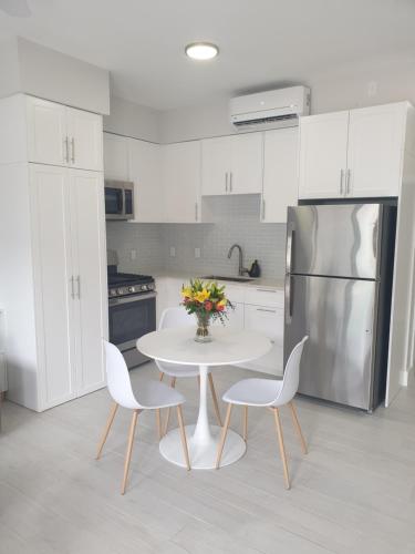 cocina con mesa blanca, sillas y nevera en Modern 1 bedroom walking distance to the beach! en West Bay