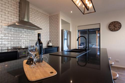 a kitchen with two wine glasses on a counter at Alpine Knights Stylish Luxury in Bright