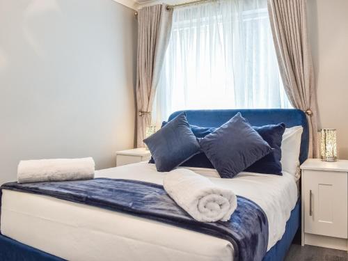 ein Bett mit blauen und weißen Kissen und einem Fenster in der Unterkunft Badger Cottage in Thornaby on Tees