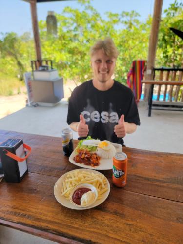 a man giving thumbs up while sitting at a table with a plate of food at Top View Kohrong in Koh Rong