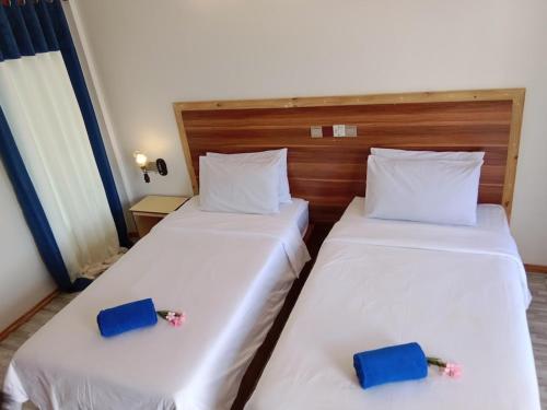 two beds in a hotel room with flowers on them at Hanifaru Beach Inn in Baa Atoll