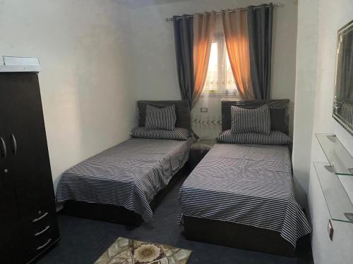 two beds in a small room with a window at horus desert hotel in Cairo