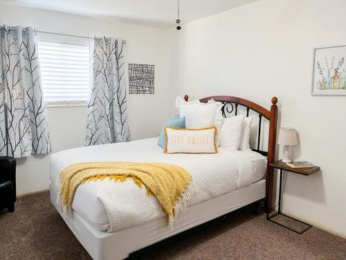 a white bedroom with a bed with a yellow blanket at Swiss Corner Cottage - Private-Heated Indoor Pool in Santa Clara