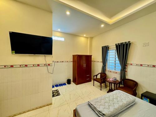 Schlafzimmer mit einem Bett und einem Flachbild-TV in der Unterkunft NHÀ NGHỈ TÚ SỰ in Vĩnh Long