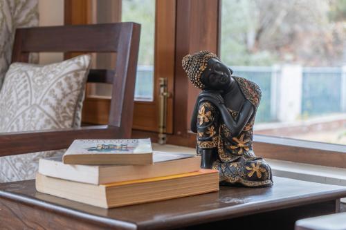 a figurine sitting on a table with books at SaffronStays Wood Sparrow in Bhīm Tāl