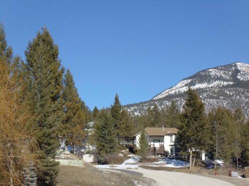 a house on a road with a mountain in the background at EVCharger, Free Parking, Ski, Golf, BBQ, Awesomeness in Invermere