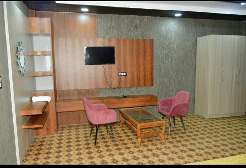 Zimmer mit einem Schreibtisch und 2 rosa Stühlen in der Unterkunft Hotel Pearl Residency in Mukteswar