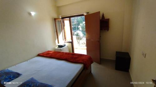 um pequeno quarto com uma cama e uma janela em Kainchi daam Road Nainital full 2bhk em Nainital