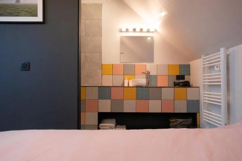 a bathroom with a sink and a tiled wall at Loft du presbytère - Calme et nature in Beauraing