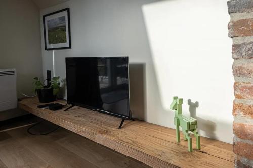 a living room with a flat screen tv on a wooden table at Loft du presbytère - Calme et nature in Beauraing