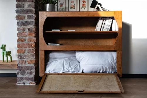a book shelf with a pillow in a room at Loft du presbytère - Calme et nature in Beauraing