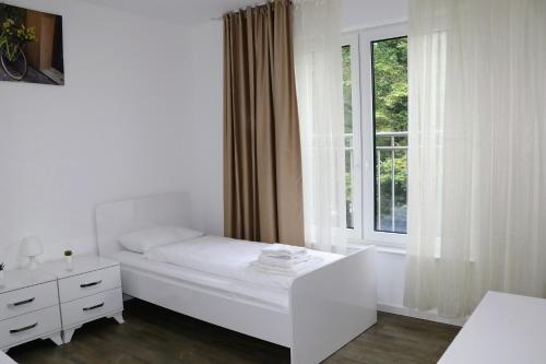 biała sypialnia z łóżkiem i oknem w obiekcie Apartments & Pension Bremen Burglesum w Bremie