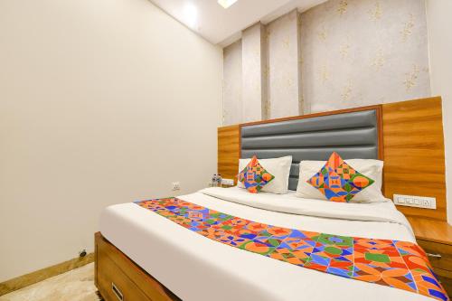 a bedroom with a large white bed with colorful pillows at FabExpress Royal MG in Ludhiana