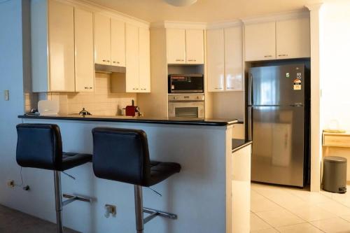 a kitchen with two bar stools and a refrigerator at Great value, Near Darling harbour, Cbd, ICC,Casino in Sydney