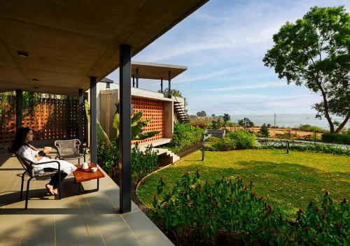 a woman sitting on the porch of a house at SaffronStays Avni in Trimbak