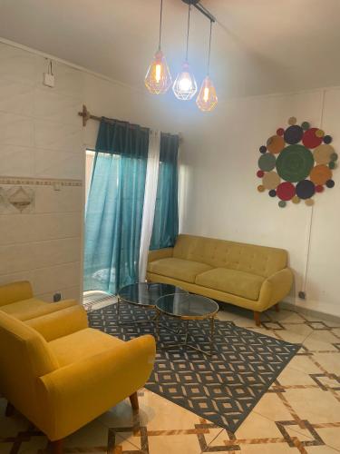 a living room with two yellow couches and a glass table at Chambre Mamoudzou in Mamoudzou