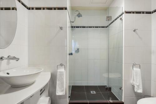 a white bathroom with a sink and a shower at Peppers Seaport Hotel in Launceston