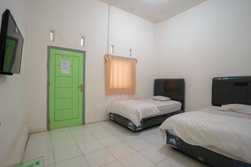 een kamer met 2 bedden en een groene deur bij Lyfriska Residence Lampung RedPartner in Lampung