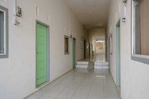un pasillo vacío con puertas verdes en un edificio en Lyfriska Residence Lampung RedPartner en Lampung