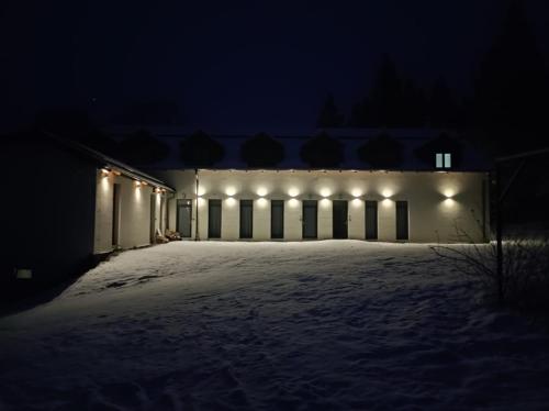 a building with lights in the snow at night at Paseky Apartments Resort in Nové Město na Moravě