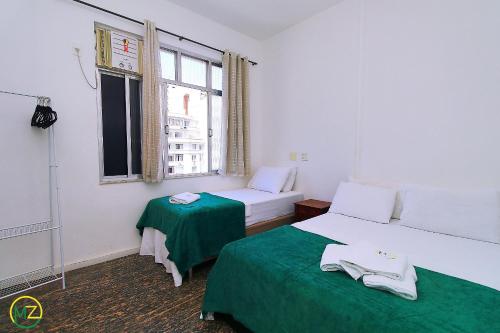 een kleine kamer met 2 bedden en een raam bij Sala quarto c/ 2 banheiros para 4 pessoas in Rio de Janeiro