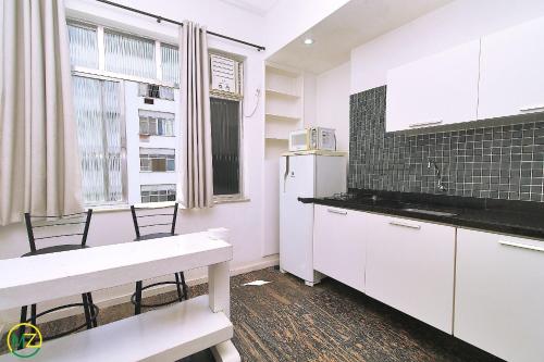 cocina con armarios blancos y nevera blanca en Sala quarto c/ 2 banheiros para 4 pessoas en Río de Janeiro