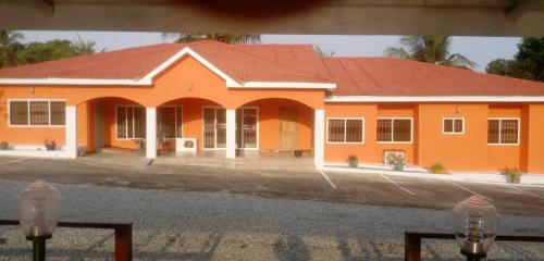 a large orange building with a red roof at Jamaica Inn Guest House in Bortianor