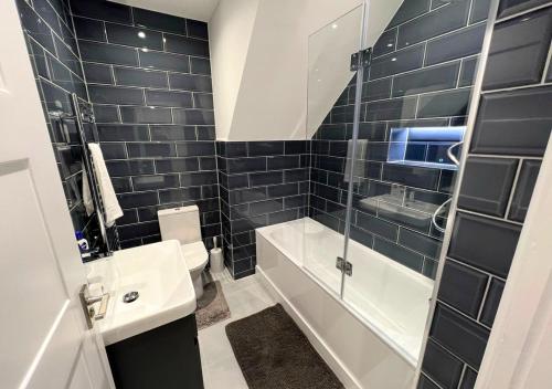 e bagno con servizi igienici, lavandino e doccia. di FW Haute Apartments at Enfield, Pet Friendly Ground Floor 3 Bedrooms and 2 Bathrooms Flat with King or Twin beds with Garden and FREE WIFI and FREE PARKING a Londra