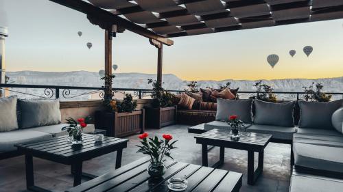 a patio with couches and tables and hot air balloons at Royal Stone Houses - Goreme in Goreme
