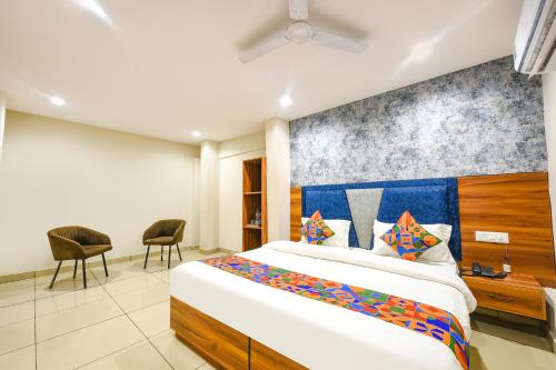 a bedroom with a large bed and two chairs at FabHotel Orio I in Ludhiana