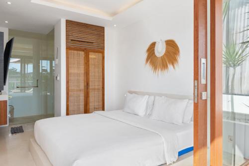 a bedroom with a white bed and a glass door at Pagi Villas by Betterplace in Canggu