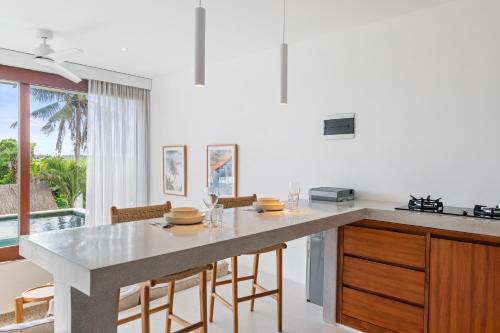 a kitchen with a large island with wooden cabinets at Pagi Villas by Betterplace in Canggu