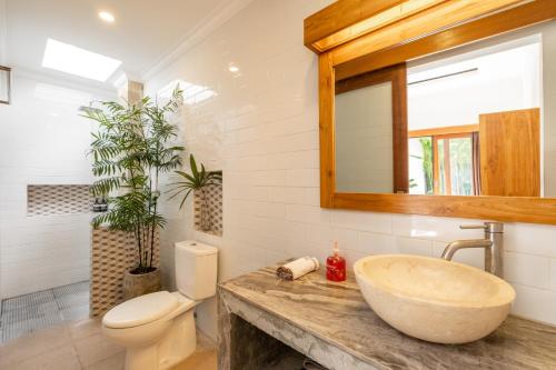 een badkamer met een wastafel, een toilet en een spiegel bij Villa Royal Canggu - 3 minutes to FINNS Beach club! in Canggu