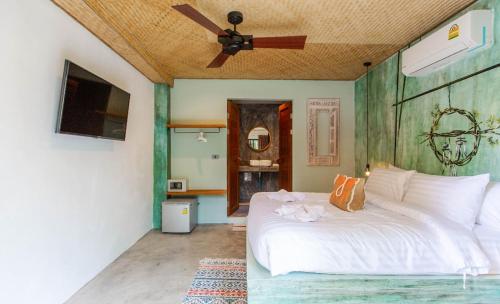 a bedroom with a white bed with a ceiling fan at Dreamcatcher Boutique Hotel in Bophut