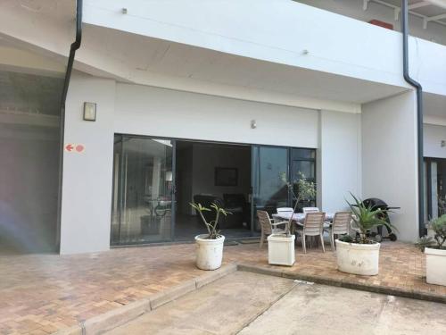 Un patio con una mesa y sillas en un edificio. en Bydistrand Stillbay, en Stilbaai