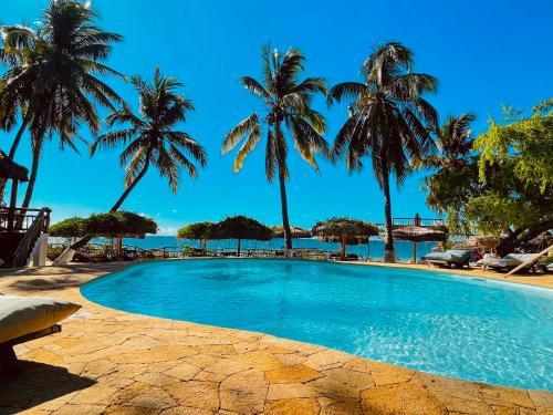 a swimming pool with palm trees and the ocean at VOVO TELO LODGE in Toliara