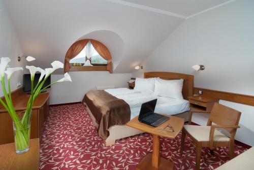 Cette chambre comprend un lit et un bureau avec un ordinateur portable. dans l'établissement Wellness Hotel Windsor, à Špindlerův Mlýn