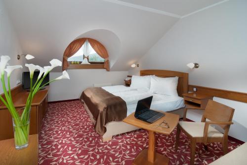 a hotel room with a bed and a desk with a laptop at Wellness Hotel Windsor in Špindlerův Mlýn