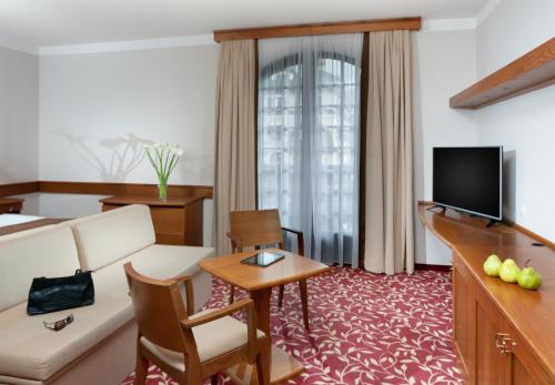 a living room with a couch and a television at Wellness Hotel Windsor in Špindlerův Mlýn